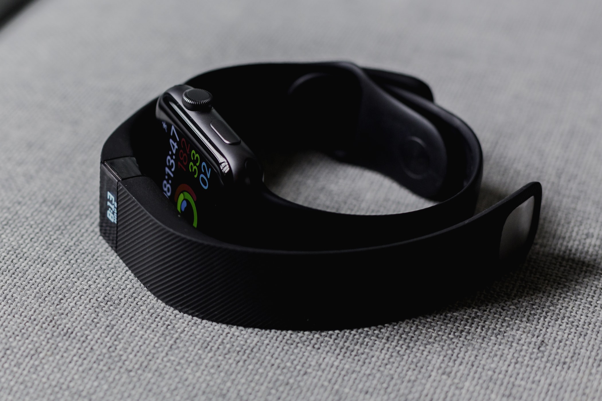 Show an Apple Watch and a Fitbit tracker one curled inside the other
