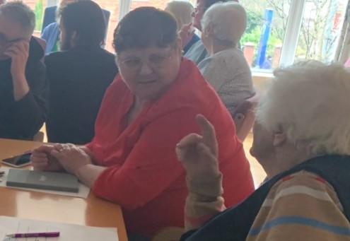 Margaret in discussion with a group of about 10 people at a care home