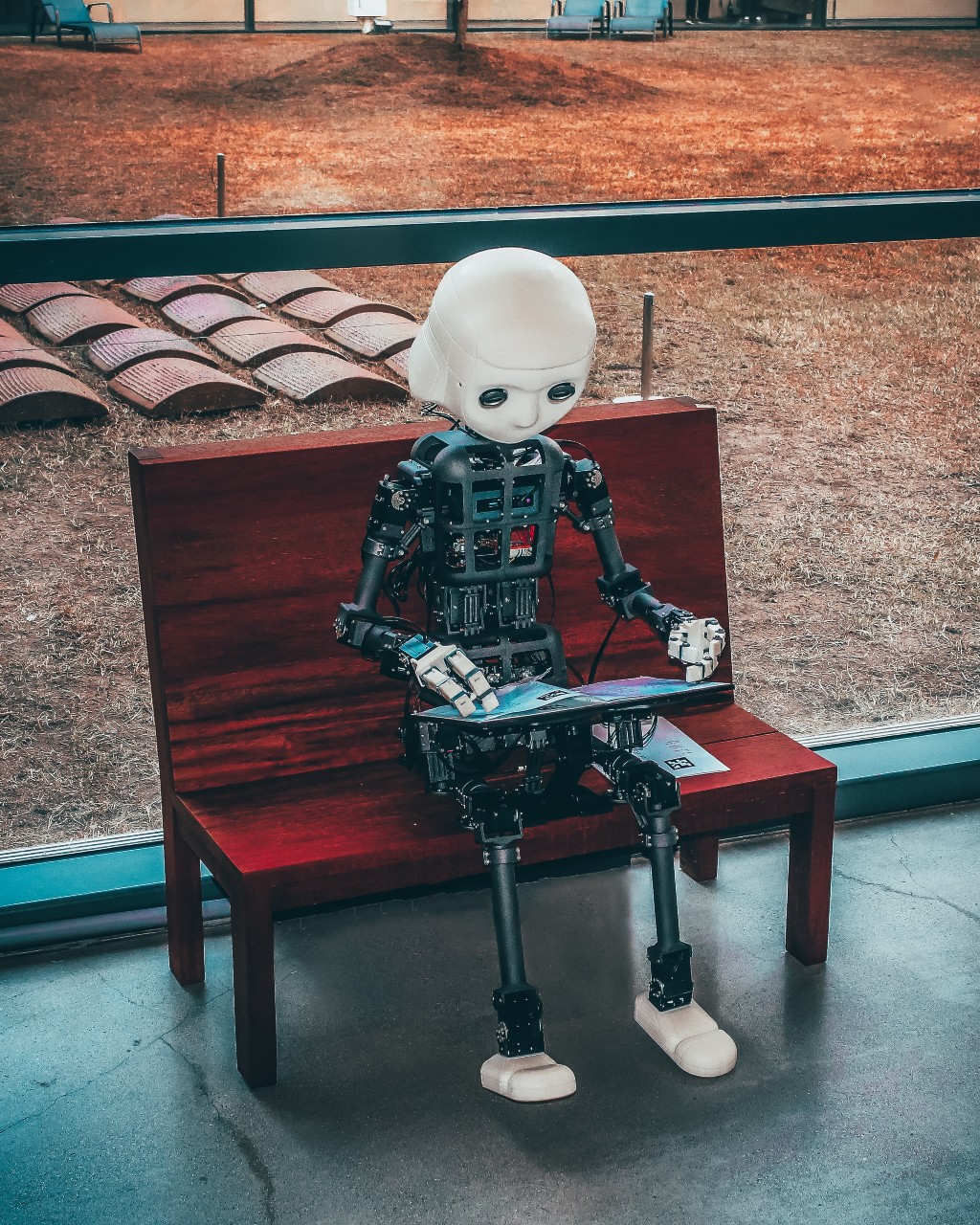 Robot sitting on a bench outdoors