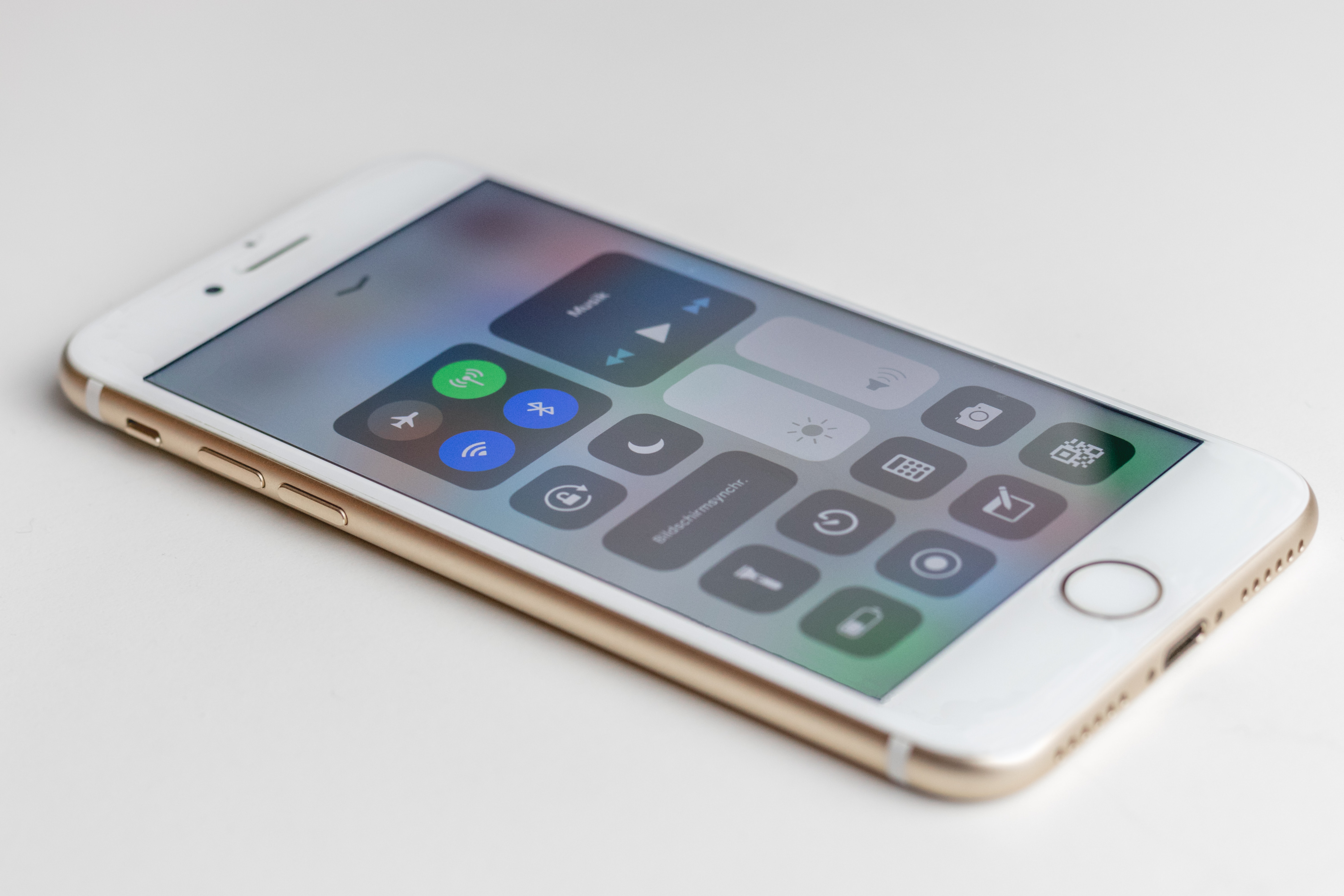 An iPhone 6 phone in gold. On the screen the settings, including Bluetooth options, are visible.