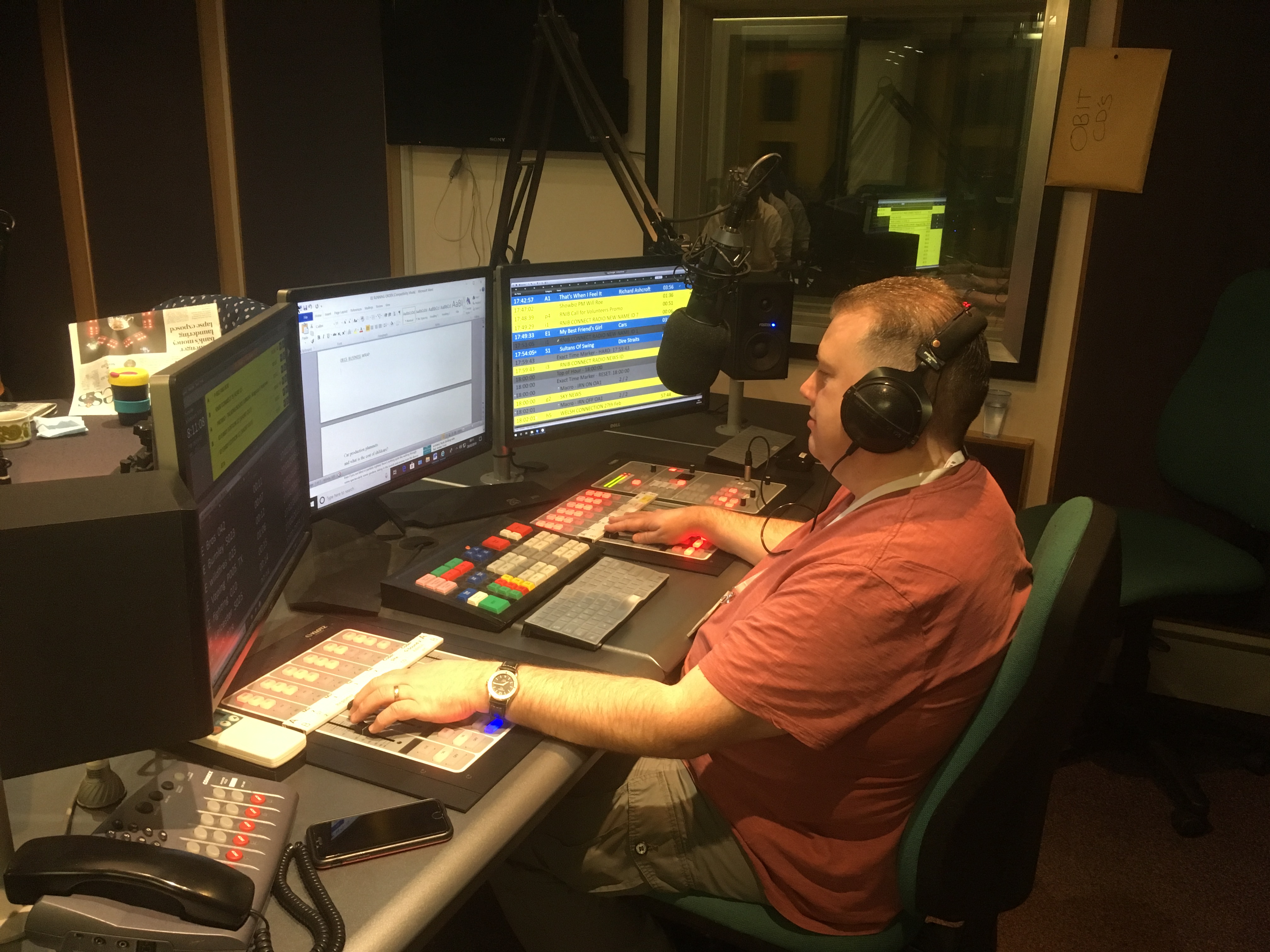 Allan inside the RNIB studio surrounded by equipment wearing headphones