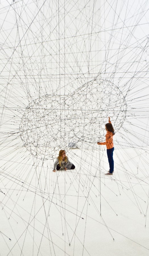 Two children looking at each other across a network of wires - Photo by Clarisse Croset