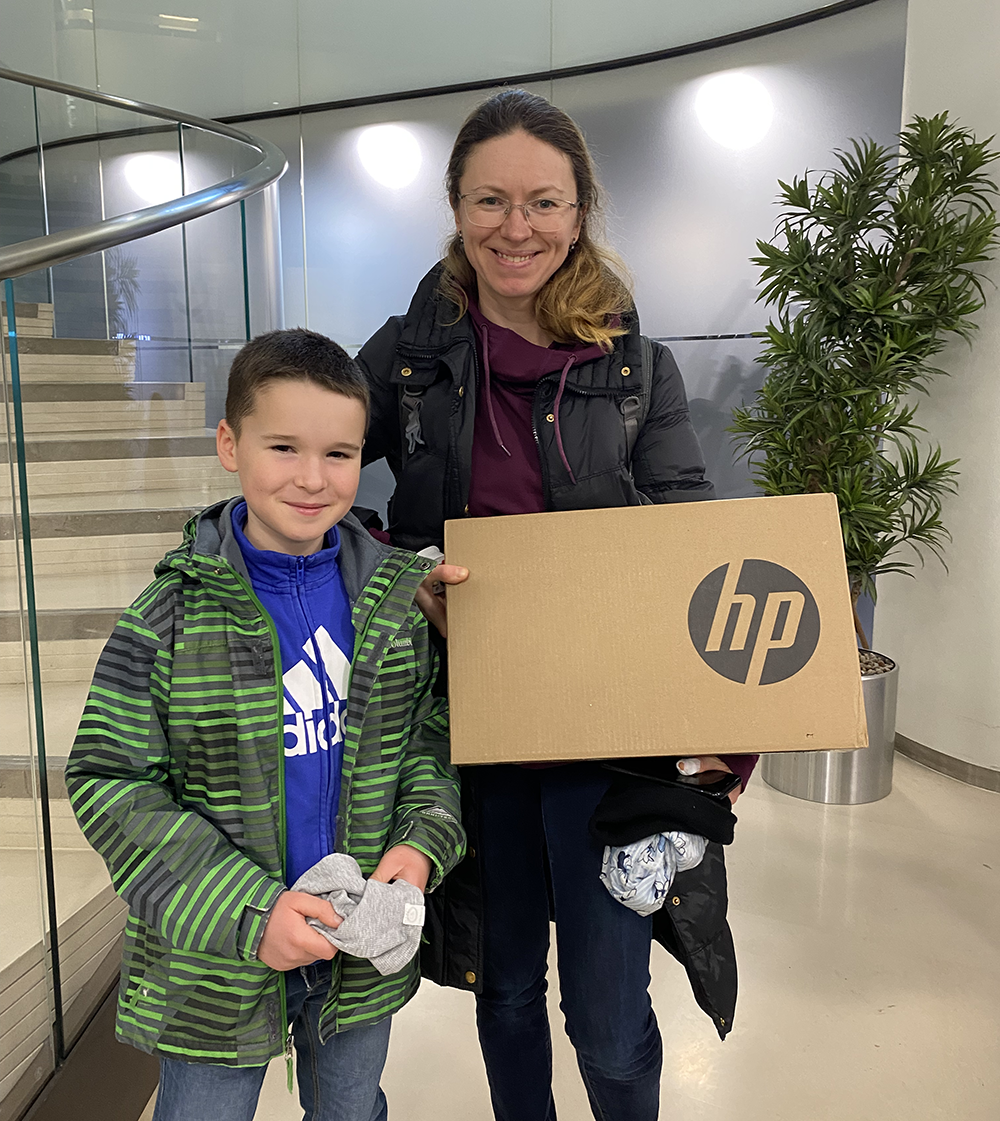 A woman and young boy smile holding laptop box