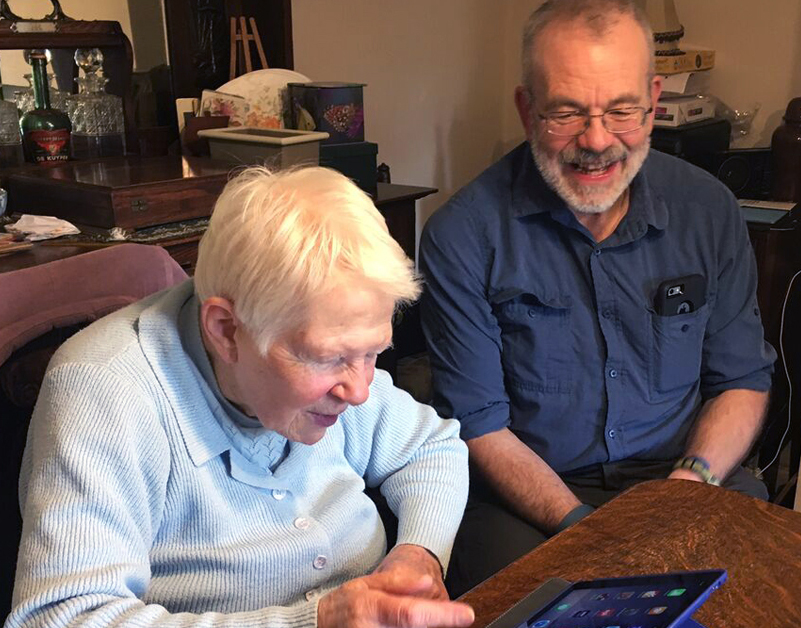 An AbilityNet volunteer helping a lady in her home to use a tablet device