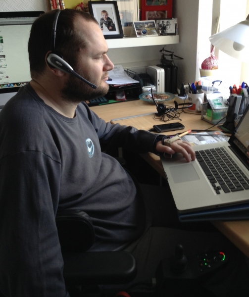 Sean at his laptop wearing a headset