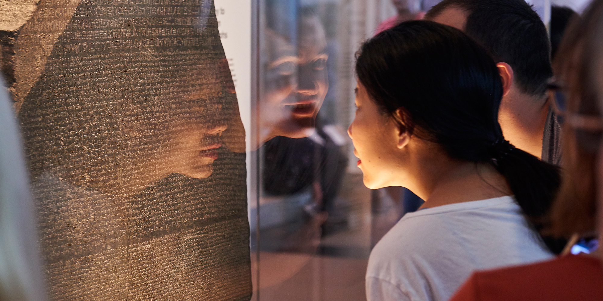 Two people looking at the Rosetta Stone in the British Museum