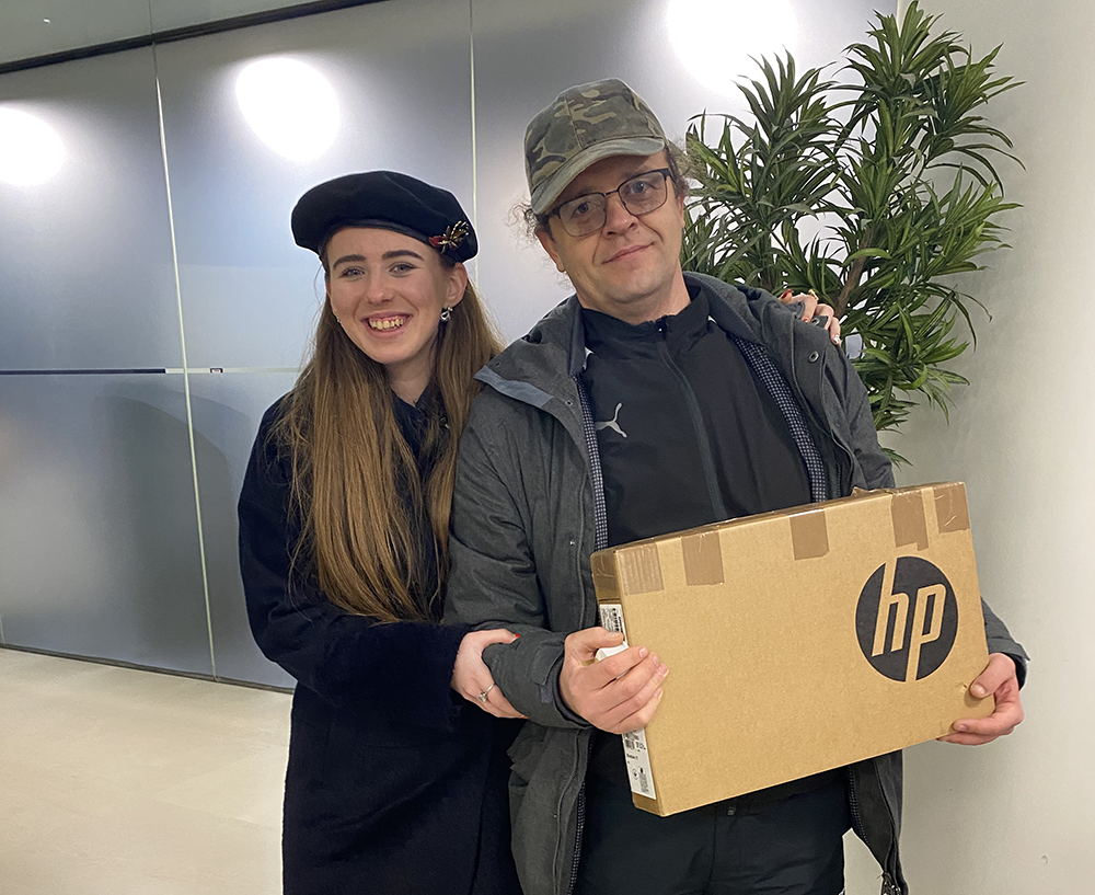 Middle aged man and teenager smiling holding laptop in box
