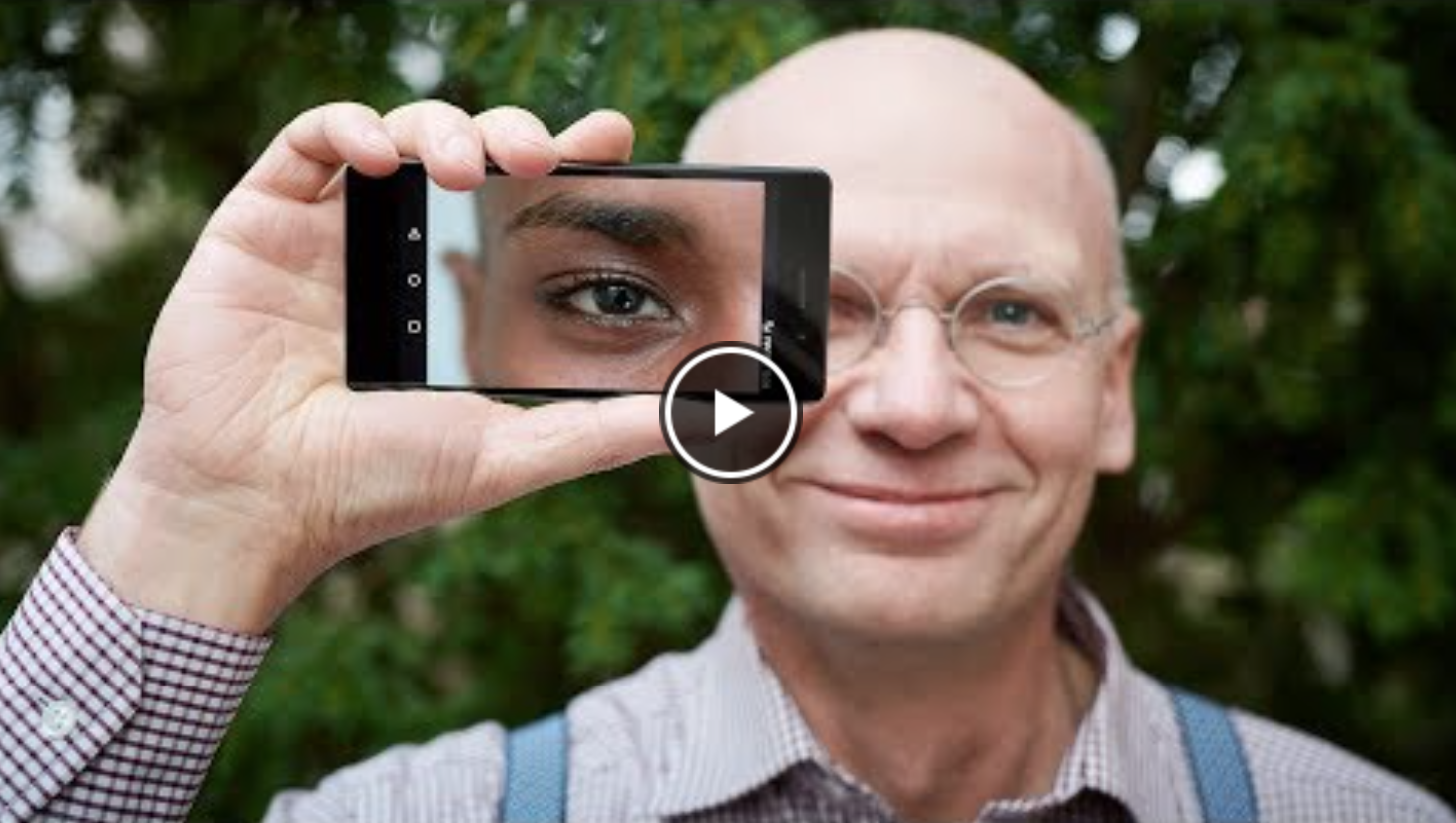 Be My Eyes man smiling holding smartphone camera to his eye