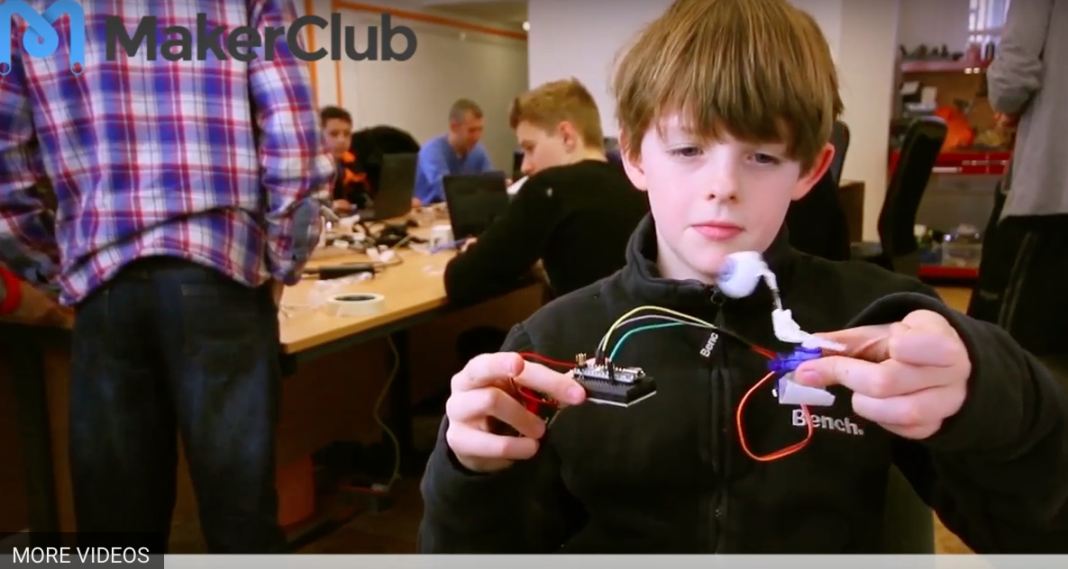 young boy holding wires and a maker club event