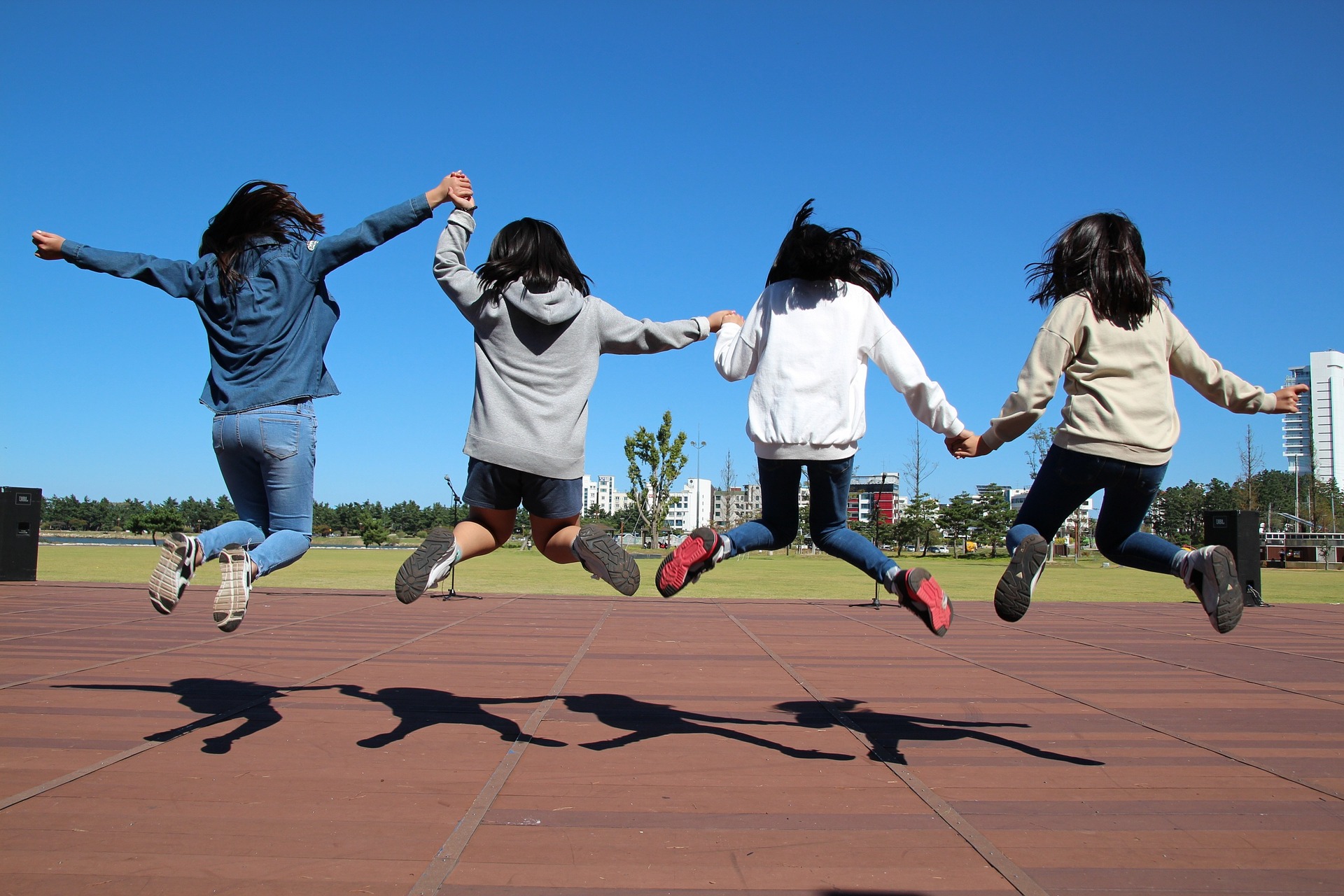 four students jumping in a park